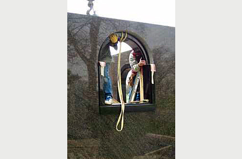 Peter Troost Monument Company craftsmen install a custom arched granite window frame in the private family mausoleum.